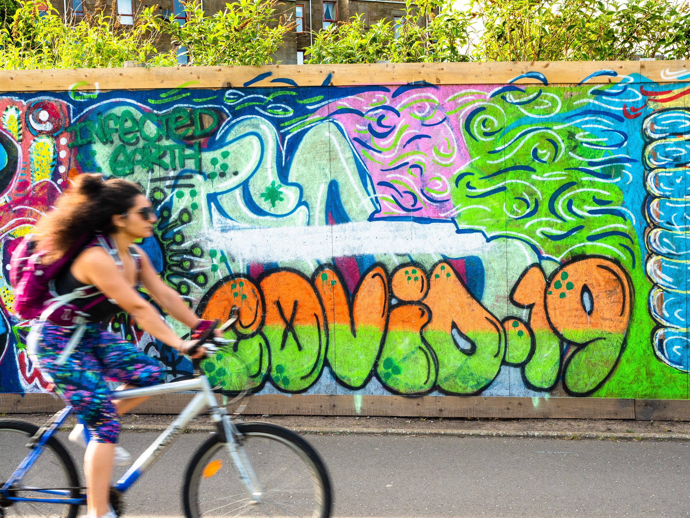 Cyclist passing COVID-19 graffitti in Dundee, Scotland. DD065