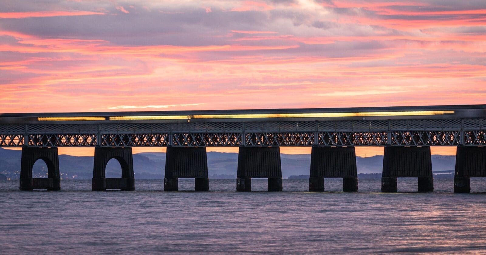 Train passing over the Tay Railway Bridge at sunset, Dundee, Scotland. DD156